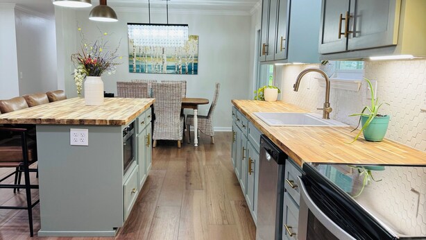A modern kitchen with a central island, wooden flooring, and grey cabinetry. - Escape to Bell Branch Place: Where Relaxation Meets Comfort (Cleveland)