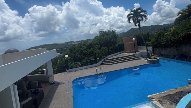 A swimming pool with a view of mountains and palm trees. - Coastal Luxury Getaway for Yoga, Golf & Family Fun (Humacao)