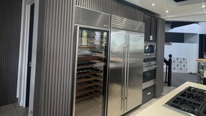 A modern kitchen with a stainless steel refrigerator, built-in oven, and a gas stove. - Coastal Luxury Getaway for Yoga, Golf & Family Fun (Humacao)