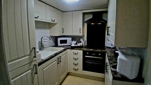A compact kitchen with white cabinets, a microwave, a toaster, and a coffee maker. - Romantic Cottage for two in North Yorkshire (Middlesbrough)
