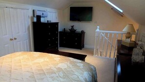 A bedroom with a bed, dresser, TV, and a staircase. - Romantic Cottage for two in North Yorkshire (Middlesbrough)