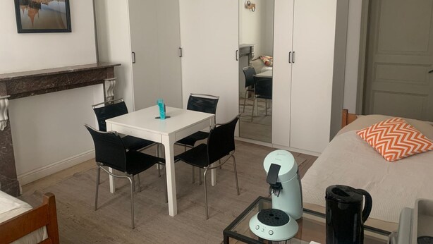 Een moderne slaapkamer met een bed, een koffieapparaat, een tafel met stoelen en een kledingkast.