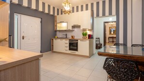 A modern kitchen with a built-in oven, a dining area with a glass table, and a hallway leading to another room. - Argilea Villa Beachfront Villa with Private Pool in Kefalonia, Argilea Villa (Lixouri)