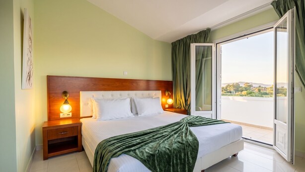 A hotel room with a bed, bedside lamps, a view through a sliding door, and a green curtain. - Argilea Villa Beachfront Villa with Private Pool in Kefalonia, Argilea Villa (Lixouri)