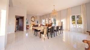 A spacious dining area with a high ceiling, a chandelier, and a large window with curtains. - Argilea Villa Beachfront Villa with Private Pool in Kefalonia, Argilea Villa (Lixouri)