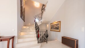 A staircase with a black metal railing, a wall-mounted light fixture, and a framed picture. - Argilea Villa Beachfront Villa with Private Pool in Kefalonia, Argilea Villa (Lixouri)