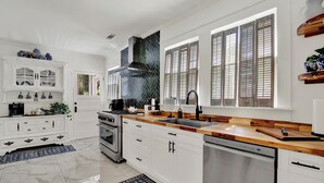 Een moderne keuken met witte kasten, een houten aanrechtblad en een inbouw vaatwasser.