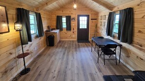 Uma cabana acolhedora com interior de madeira, área de jantar e pequena cozinha.