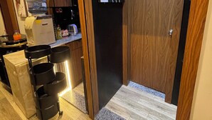 Uma cozinha moderna com dispensador de água, máquina de café e um carrinho preto com vários recipientes.