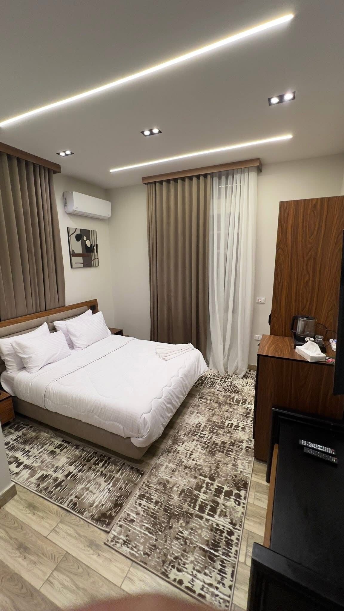 Une chambre d’hôtel moderne avec un lit bien fait, un bureau avec un ordinateur et une télévision.