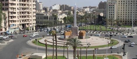 A cityscape with a central monument surrounded by palm trees and a roundabout.