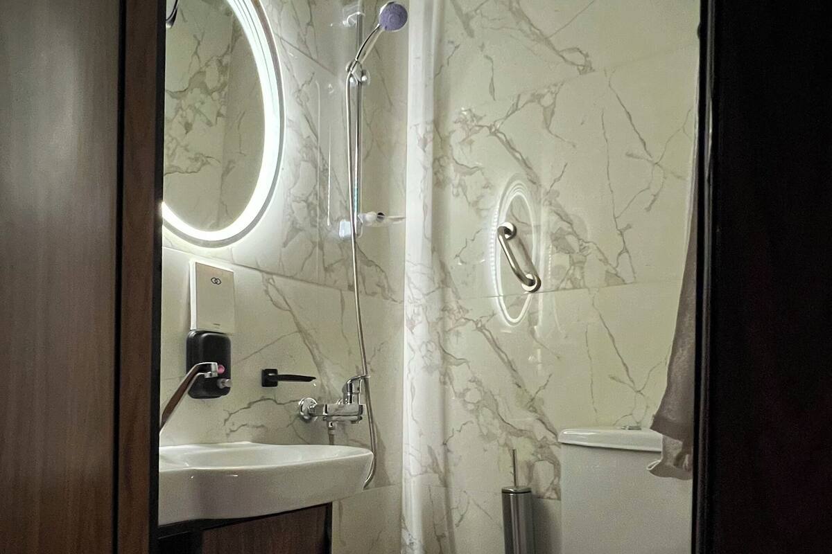 Ein Badezimmer mit Marmorwand, Waschbecken, Toilette und Dusche.
