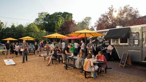 Food truck ao ar livre com quadro de cardápio e endereço de site.