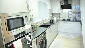 A modern kitchen with a built-in oven, microwave, and washing machine.