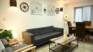 A living room with a sofa, coffee table, and chairs. There are decorative wheels on the wall and a lamp.
