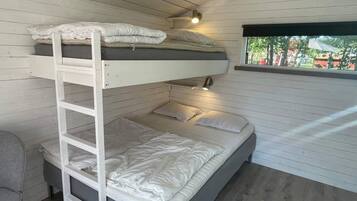 A bunk bed with a ladder, a desk, and a window with a view of trees.