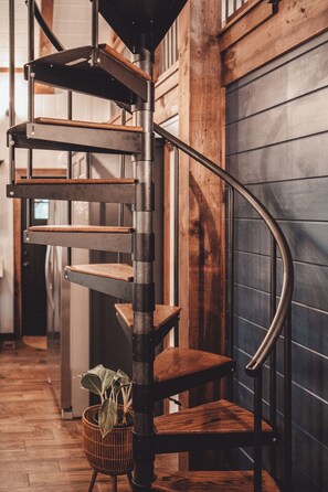 A spiral staircase with wooden steps and metal railings, leading to an upper floor.