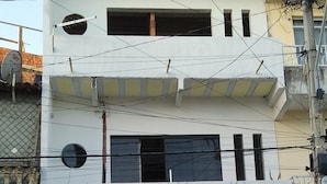 Un edificio de varios pisos con puerta de garaje, antena parabólica y un balcón con barandilla.