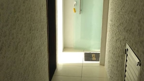 Un estrecho pasillo con suelo de baldosas que conduce a una habitación con puerta de cristal.
