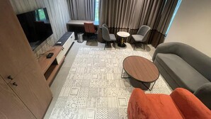 A modern living room with a sofa, a coffee table, a TV, and a desk with a chair. - KB MARINA PARK (Chennai)
