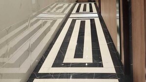 A corridor with a patterned floor, wooden doors, and recessed ceiling lighting. - KB MARINA PARK (Chennai)