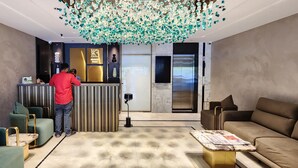 A modern lobby with a reception desk, a chandelier, and seating areas. - KB MARINA PARK (Chennai)