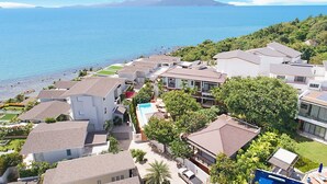 A coastal residential area with modern houses, a swimming pool, and a view of the sea.
