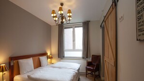 A bedroom with a double bed, a chair, a window with curtains, a radiator, and a chandelier. - Ground Floor Romantic Apt in Valkenburg (Valkenburg aan de Geul)