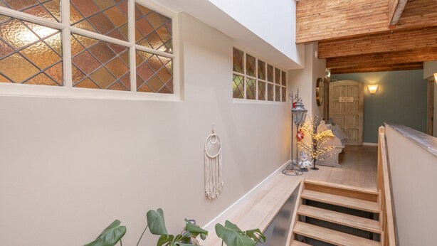 A staircase with wooden steps leading to a landing area with a bench and a macrame wall hanging. - Ground Floor Romantic Apt in Valkenburg (Valkenburg aan de Geul)