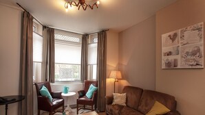 A cozy living room with a brown leather sofa, two armchairs, a wooden coffee table, and a floor lamp. - Ground Floor Romantic Apt in Valkenburg (Valkenburg aan de Geul)