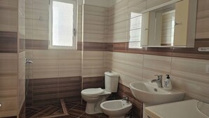 A bathroom with a shower, toilet, bidet, and sink. - Albania Dream Saranda Apartments (Sarandë)