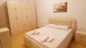 A bedroom with a bed, a wardrobe, a nightstand, and a painting on the wall. - Albania Dream Saranda Apartments (Sarandë)