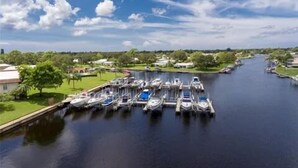 Una marina con barcos amarrados a lo largo de un río, rodeada de vegetación y edificios.