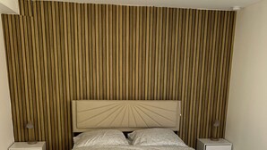 Une chambre à coucher comprenant un lit, deux tables de chevet, un mur avec des lambris verticaux et un plafond.