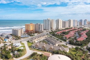 A coastal cityscape with high-rise buildings, a beachfront, and a residential area with red-roofed houses. - OCEAN VIEW | 6 bedrooms, 2 Game rooms, Parking, AC (Daytona Beach Shores)