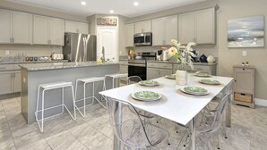 Une cuisine moderne avec un îlot central, des tabourets de bar et une enseigne « PLAGE » au-dessus de la porte.
