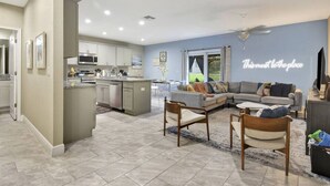A spacious living area with a large sofa, a dining table, and a kitchen area with modern appliances. - 6 Bedrooms - OCEAN VIEW, 2 Game Rooms, Parking, AC (Daytona Beach Shores)