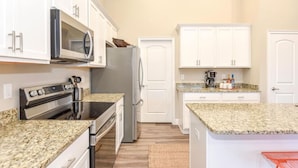 A kitchen with white cabinets, a stainless steel refrigerator, a microwave, and a stove. - 6 Bedrooms - OCEAN VIEW, 2 Game Rooms, Parking, AC (Daytona Beach Shores)