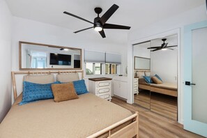 Une chambre à coucher avec un lit, un ventilateur de plafond, une commode et un miroir.