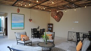 Un'ampia zona giorno con un tavolino rotondo, posti a sedere comodi, una libreria e un grande quadro raffigurante una spiaggia.