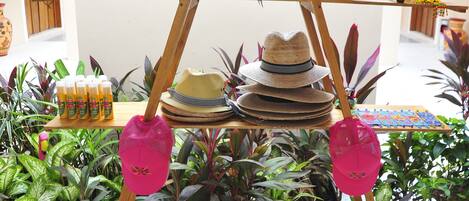 A display of hats and shoes on a wooden stand in a well-lit indoor space with tiled flooring and potted plants.