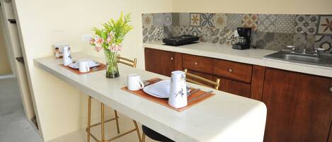 A kitchen with a long counter, a sink, and a coffee maker.