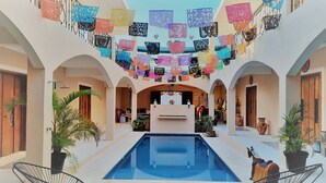 A courtyard with a swimming pool, surrounded by arches and decorated with colorful paper cutouts. - Casa Xanath (Tulum)