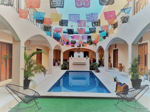 A courtyard with a swimming pool, surrounded by arches and decorated with colorful paper cutouts. - Casa Xanath (Tulum)