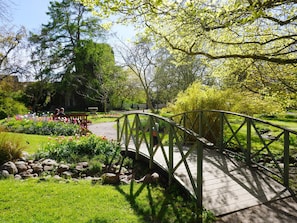 A wooden bridge over a garden path with lush greenery and flowering plants. - 4 Star Holiday Home in Visby (Visby)