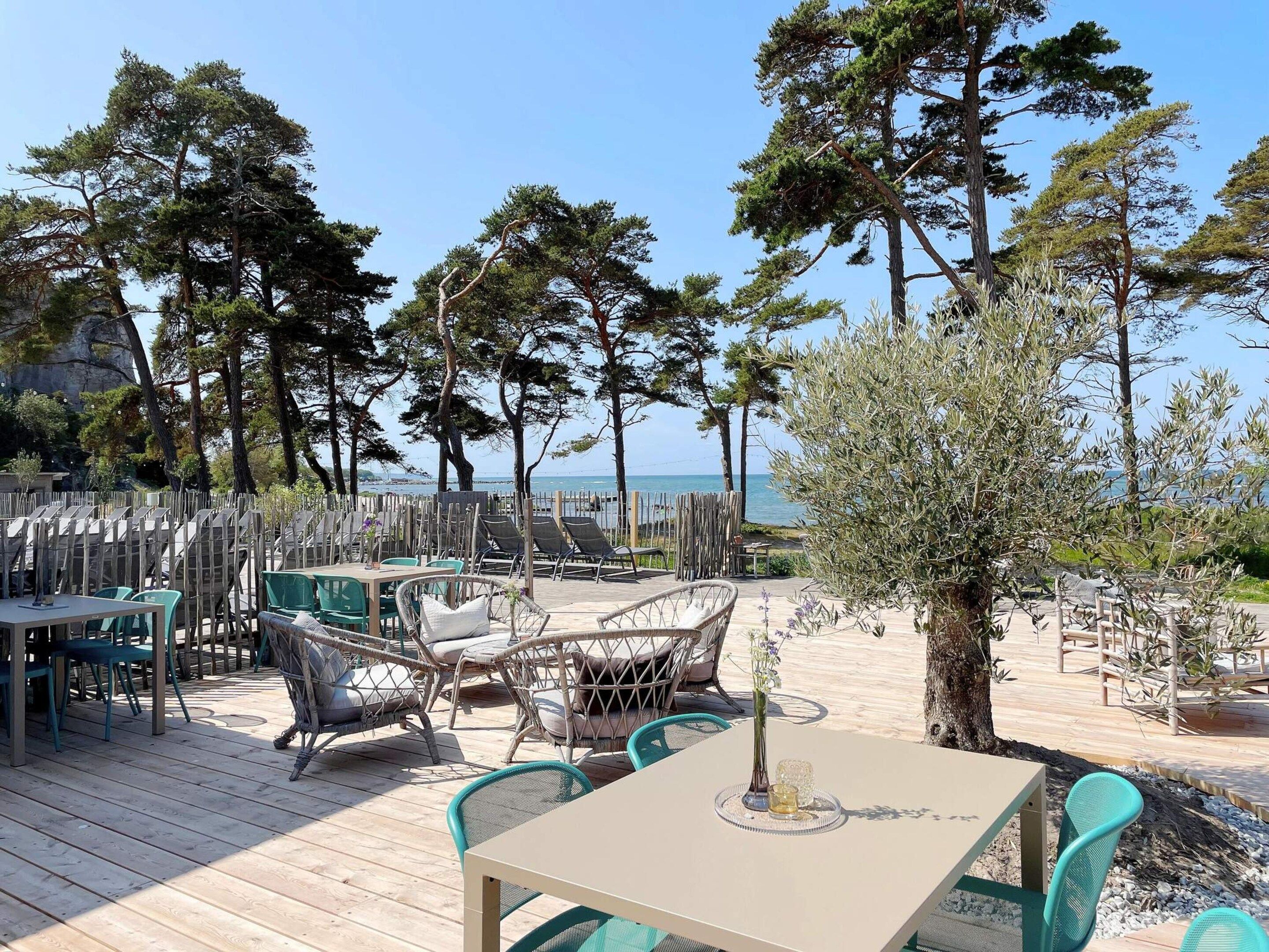 An outdoor seating area with tables and chairs, overlooking a body of water.