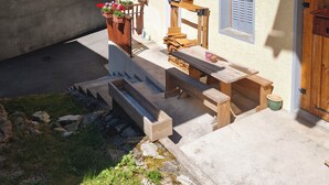 A wooden chalet with a balcony, outdoor seating, and a mountain view.