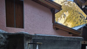 A building with a pink exterior, a wooden door, and a concrete water spout.