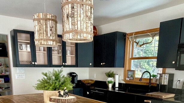 A kitchen with dark cabinets, a wooden island, and pendant lights.