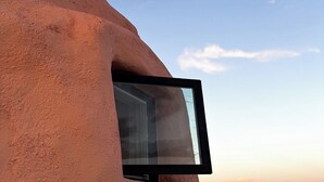 Una ventana con una vista despejada al atardecer y colinas lejanas.